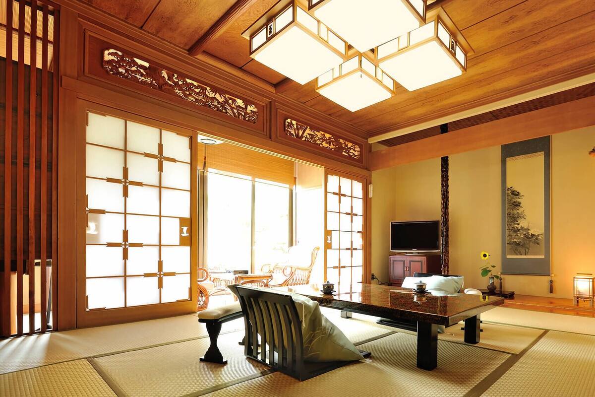 A traditional Japanese room with tatami flooring, a low table, a television, and a sliding door.