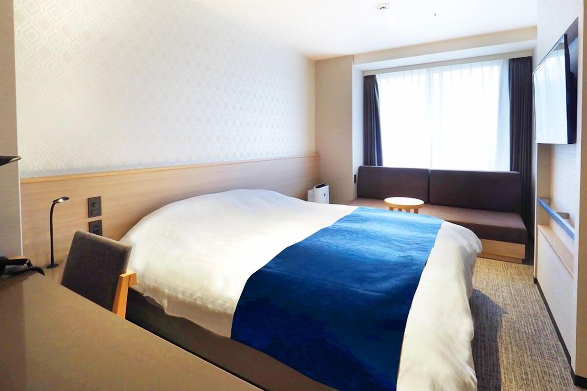 Une chambre d’hôtel comprenant un lit, un coin salon, un bureau et un téléviseur.
