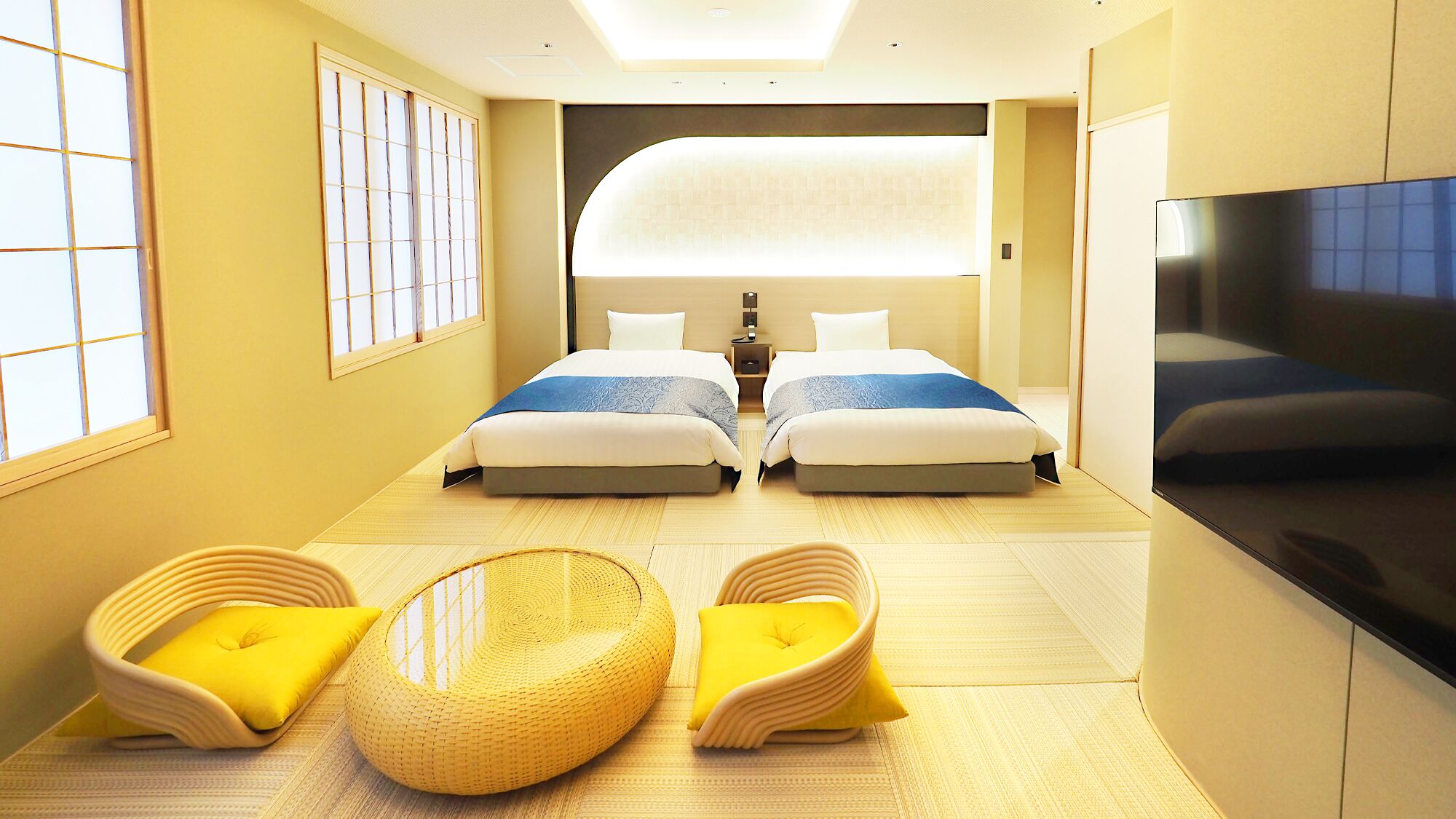 Quarto de hotel com duas camas, televisão, sofá e um futon.