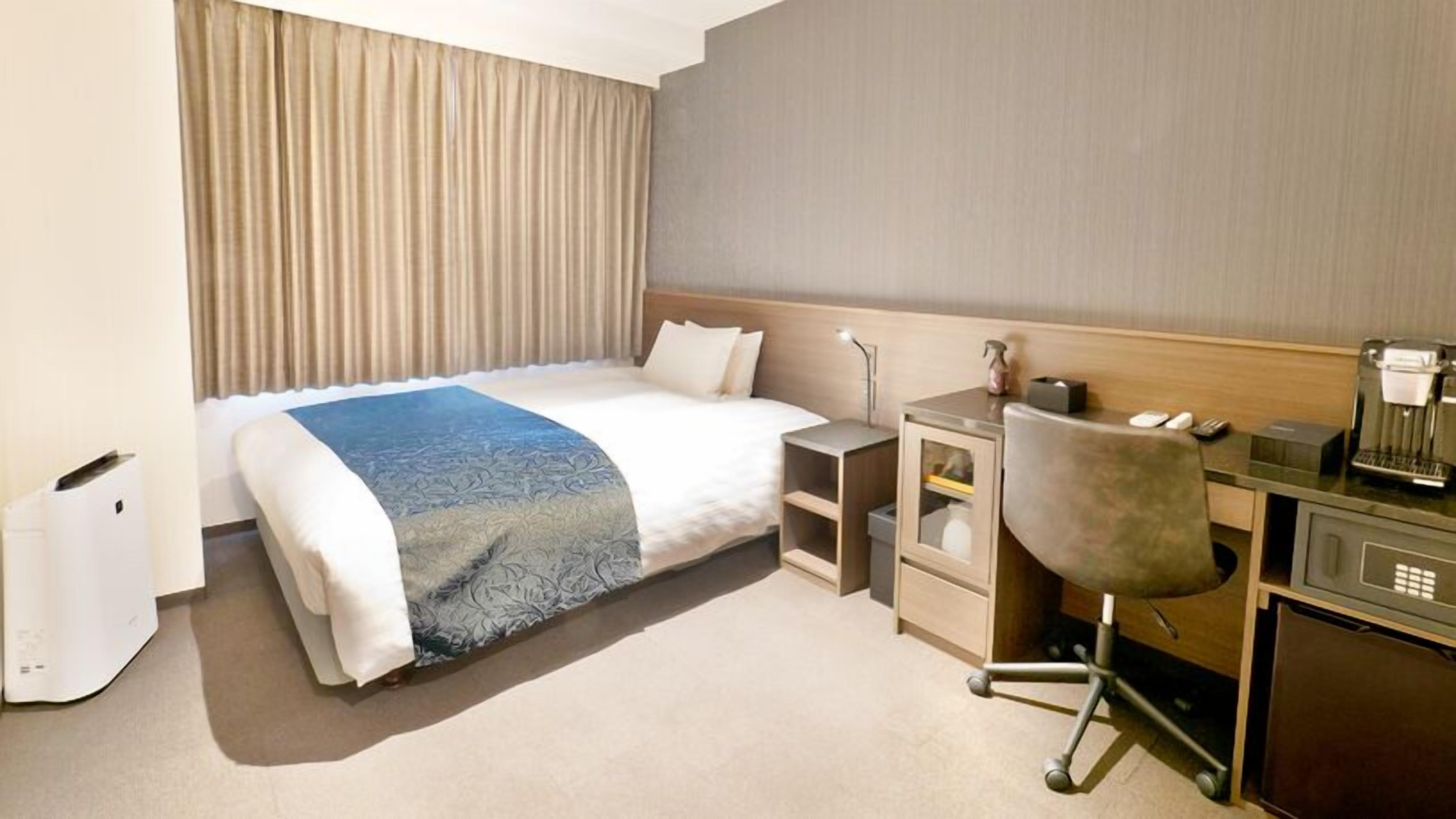 Quarto de hotel com cama, escrivaninha, cadeira e máquina de café.