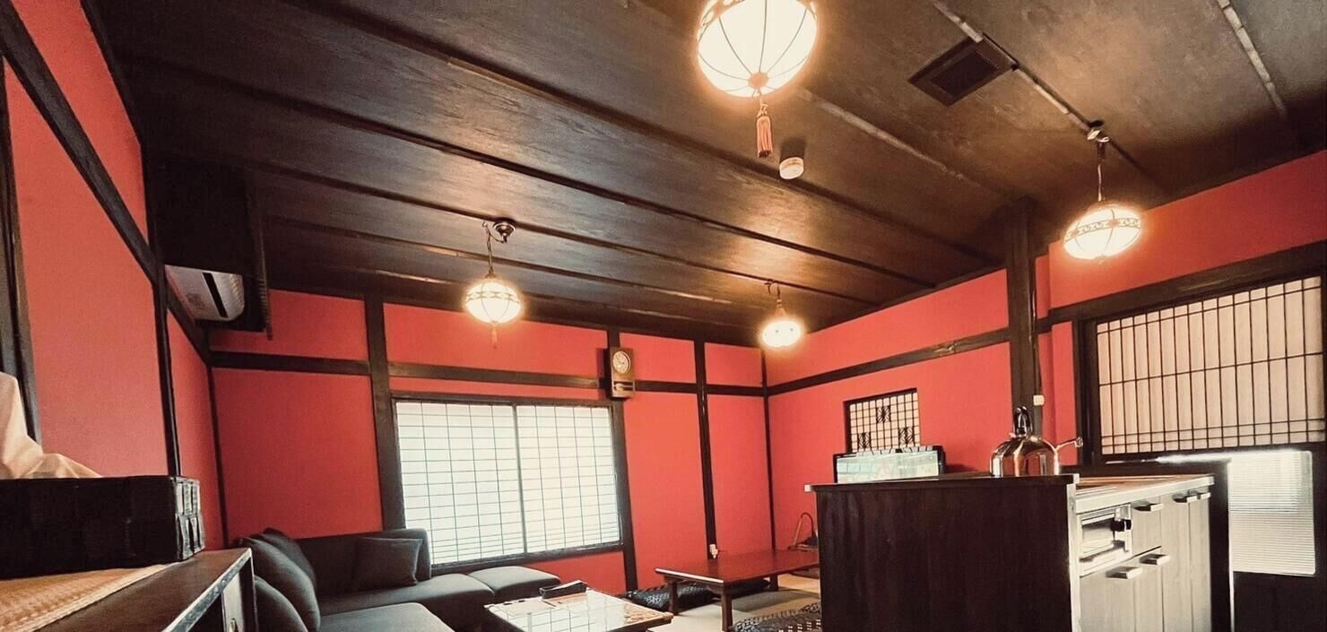 Una habitación con techo de madera, una puerta corredera tradicional japonesa, una mesa pequeña y un mostrador con un hervidor.
