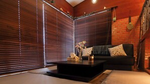 A room with a dark-colored sofa, a small coffee table, and a decorative vase. - Greenmist Atami Shizenkyo (Atami)