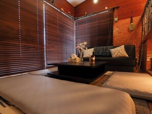 A room with a dark-colored sofa, a small coffee table, and a decorative vase. - Greenmist Atami Shizenkyo (Atami)