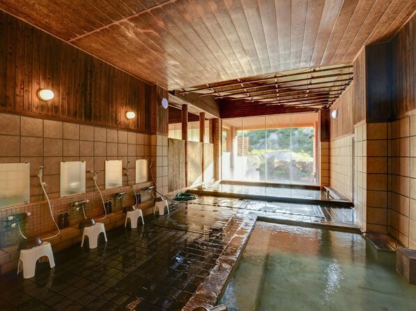 A traditional Japanese onsen with wooden walls, tiled floors, and multiple washbasins.