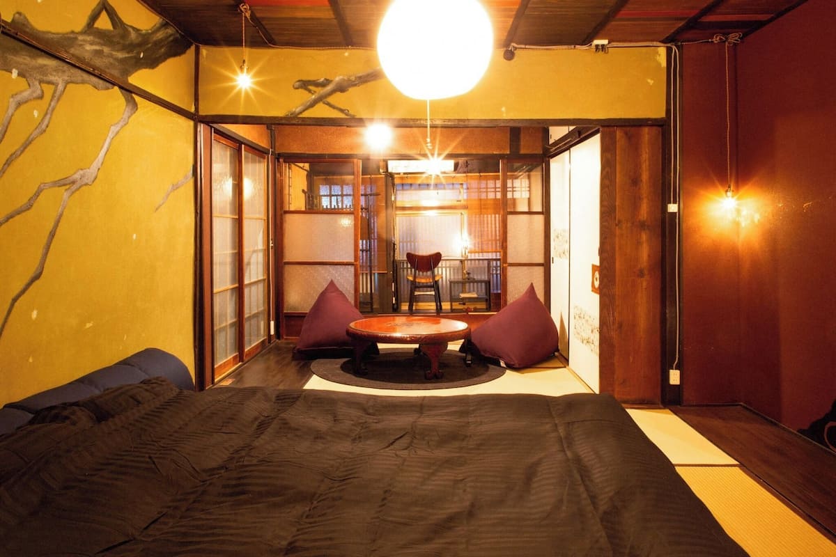 Una habitación japonesa tradicional con suelo de tatami, una mesa de madera baja y puertas correderas.