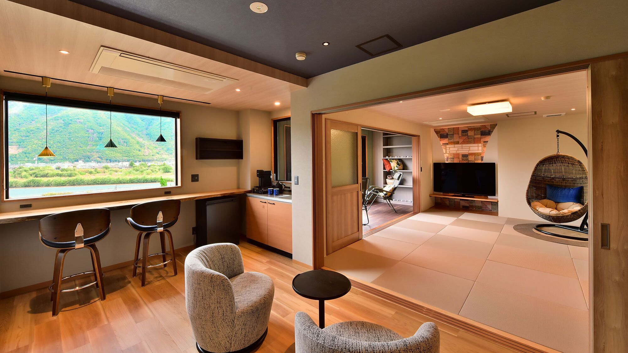 A modern interior with a kitchen area, a dining space, and a living room featuring a large TV and a hanging chair.