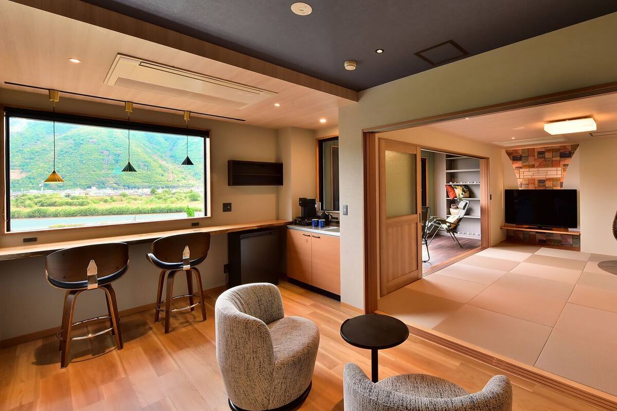 A modern interior with a kitchen area, a dining space, and a living room featuring a large TV and a hanging chair.