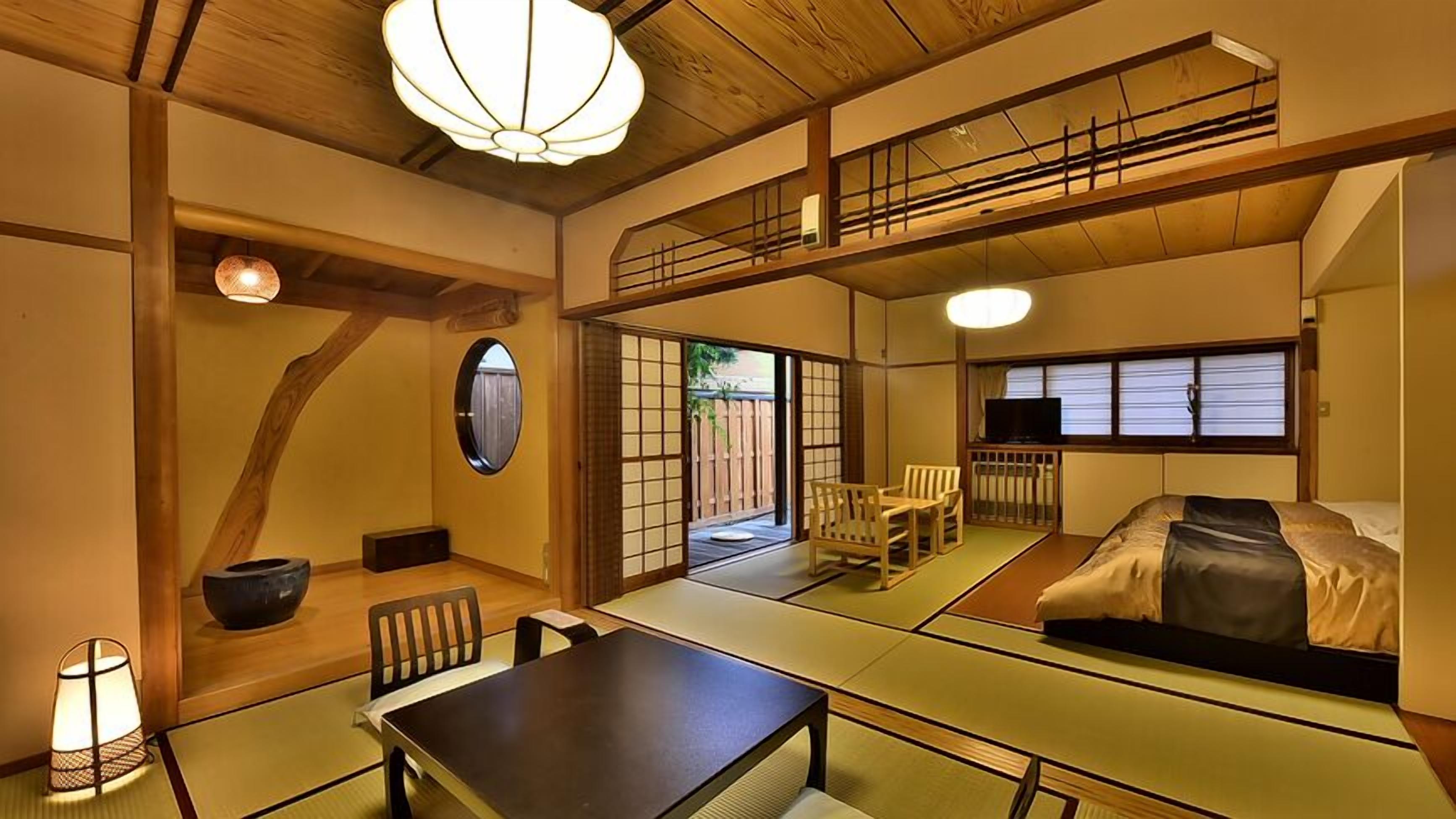 A traditional Japanese room with tatami flooring, a low table, a sofa, and a TV.