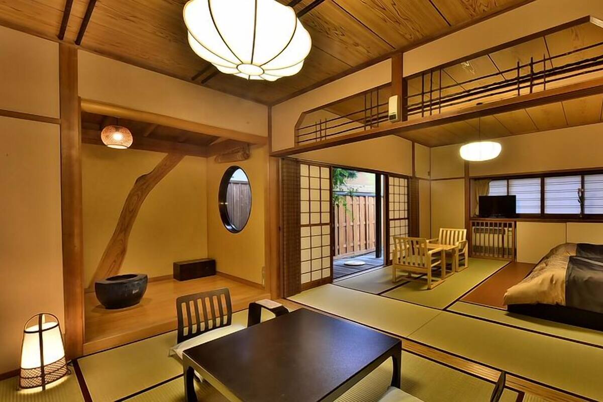 A traditional Japanese room with tatami flooring, a low table, a sofa, and a TV.