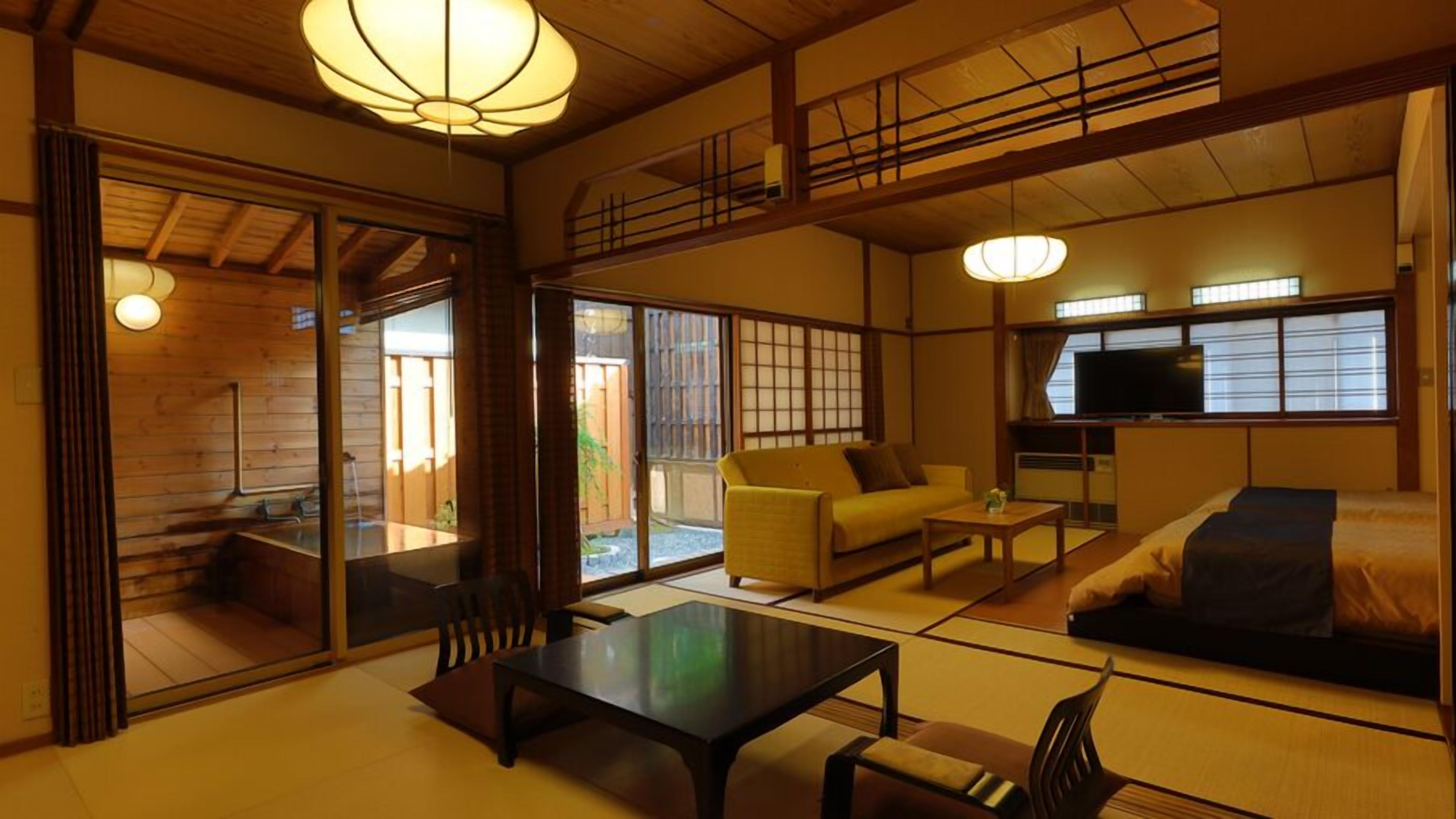 A traditional Japanese-style room with tatami flooring, a low table, a sofa, and a television.
