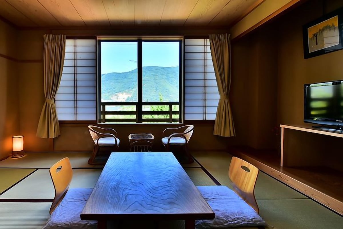 A traditional Japanese room with tatami flooring, a low table, and a television.