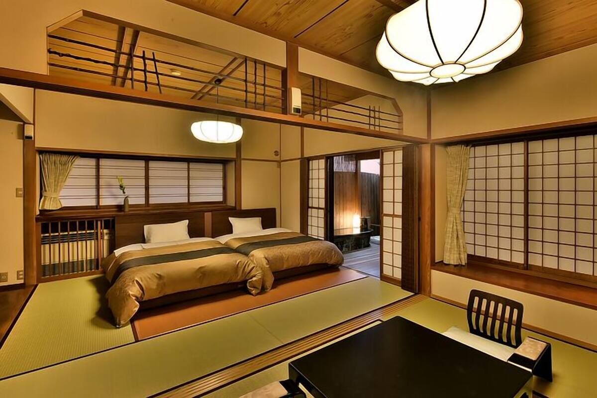 A traditional Japanese-style room with tatami flooring, a futon bed, a low table, and sliding doors.