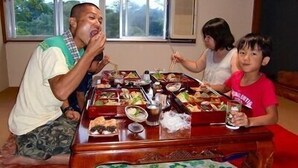 A dining table with multiple dishes and a beverage, set in a room with a window and a view of greenery outside. - K2 Cottage (Hachijo)