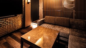 Un interior moderno con suelo de madera, un conjunto de sofás, una mesa y un televisor instalado en la pared.