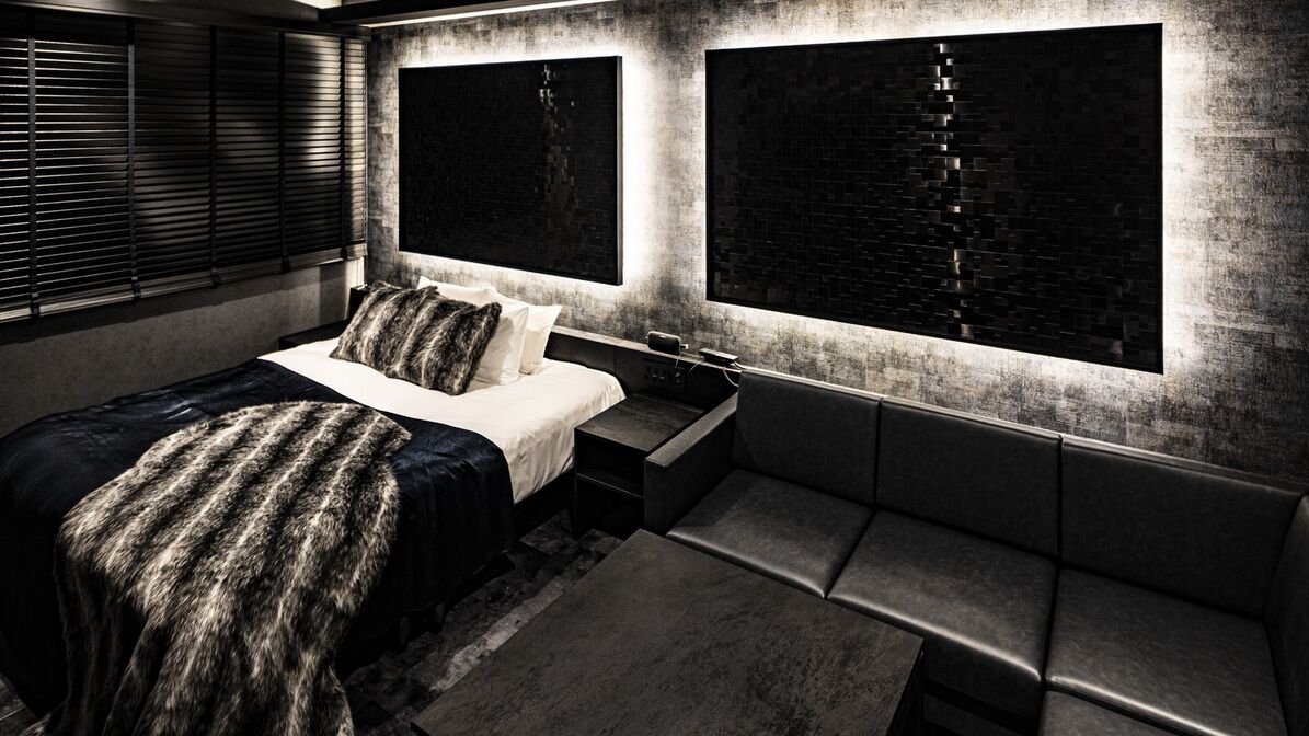 Un dormitorio moderno con una cama, mesitas de noche, un banco y ventanas grandes con persianas.