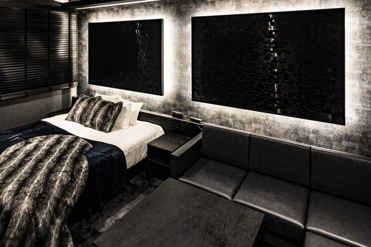 Un dormitorio moderno con una cama, mesitas de noche, un banco y ventanas grandes con persianas.