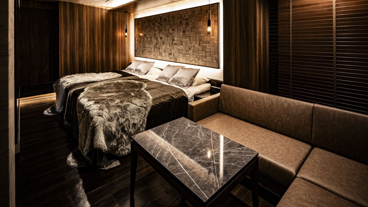 Una habitación moderna con cama, sofá y una mesita de mármol.