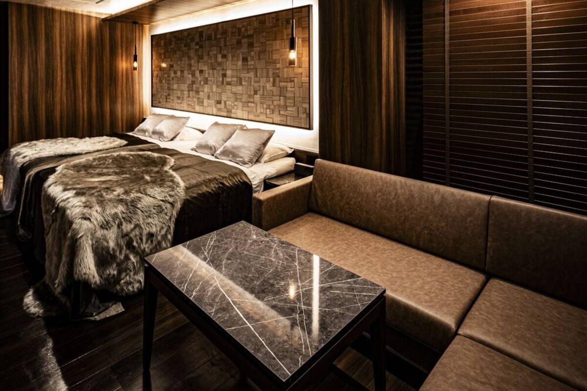 Una habitación moderna con cama, sofá y una mesita de mármol.
