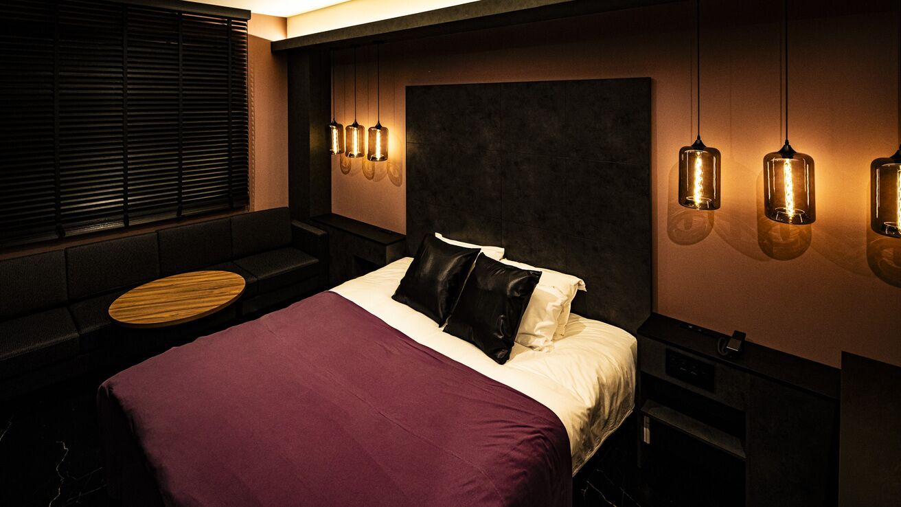 Un dormitorio moderno con cama, zona de estar e iluminación colgante.
