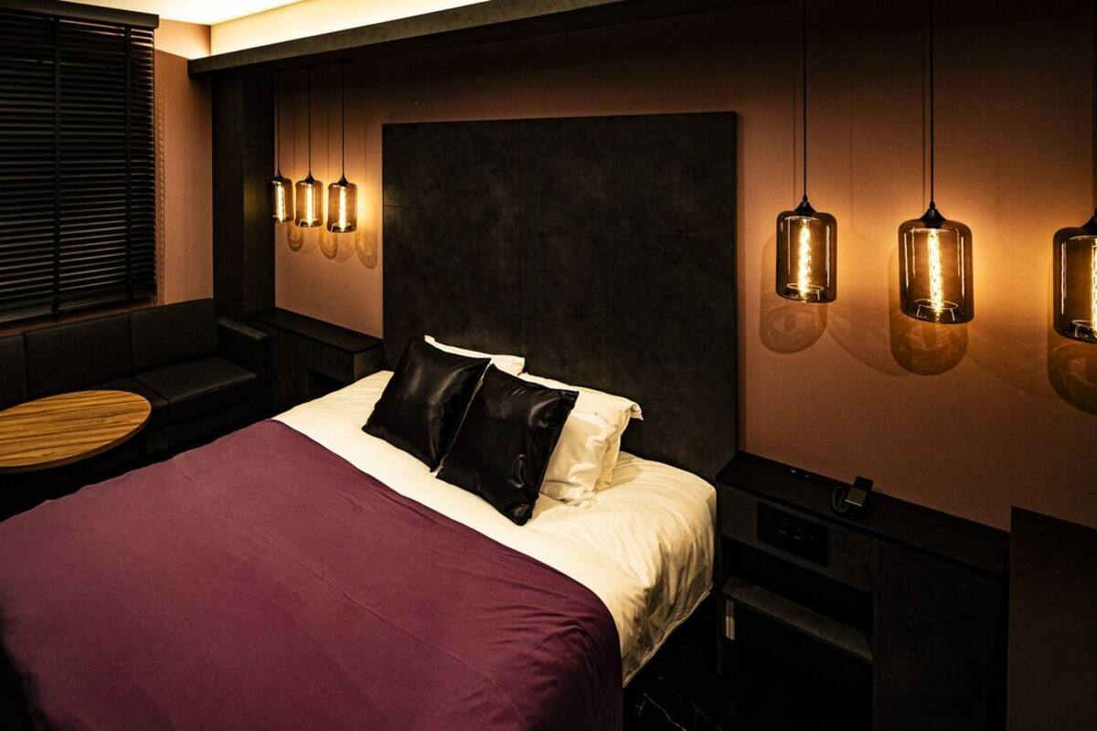 Un dormitorio moderno con cama, zona de estar e iluminación colgante.