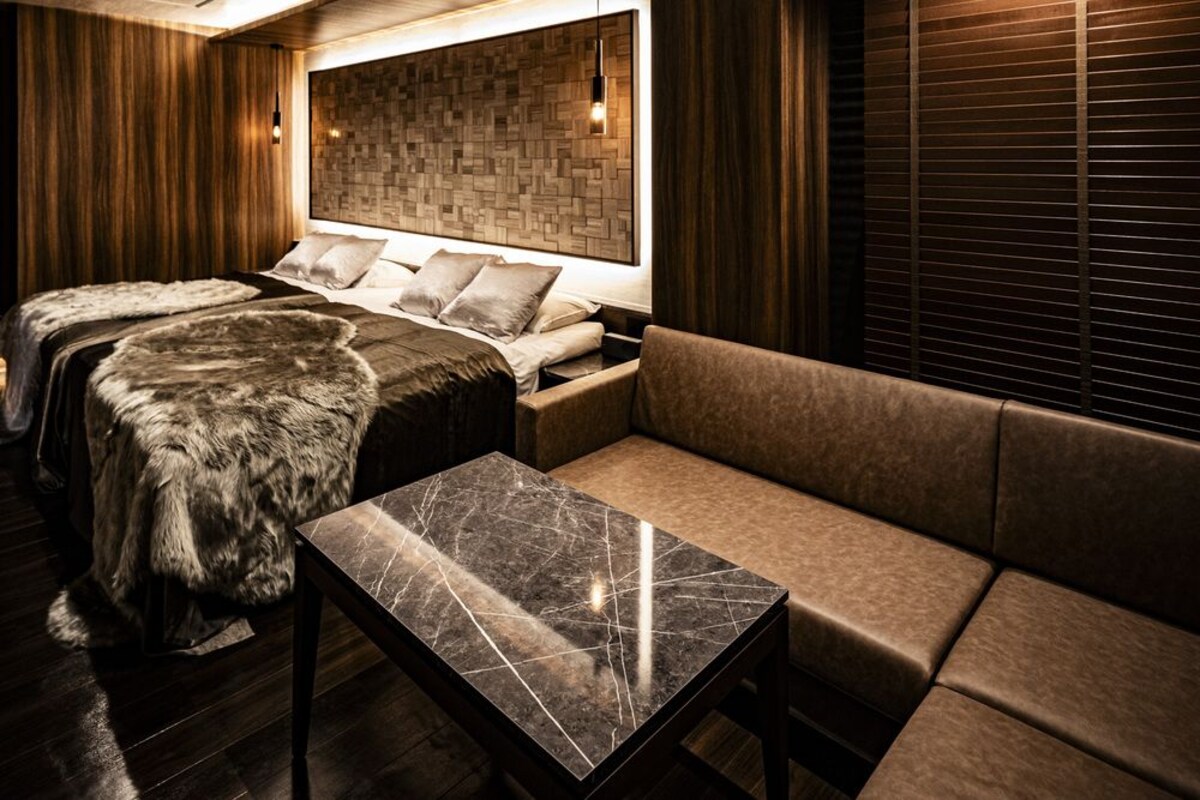 A modern room with a bed, a sofa, and a marble table.