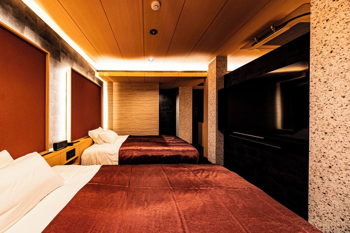 Habitación de hotel con dos camas, televisión y techo de madera.
