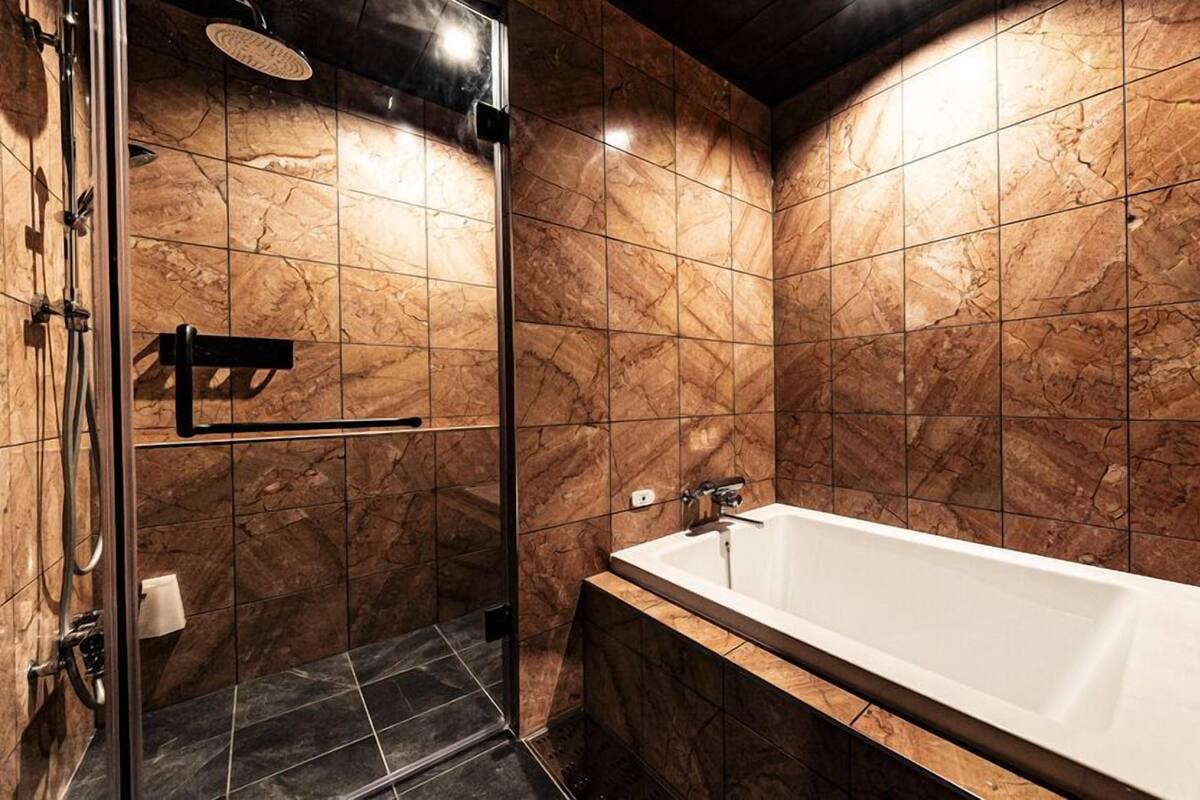 Un baño moderno con ducha de vidrio, bañera independiente y paredes de mármol.