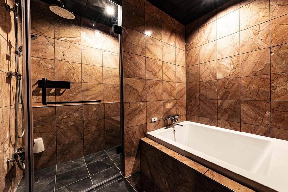 Un baño moderno con ducha de vidrio, bañera independiente y paredes de mármol.