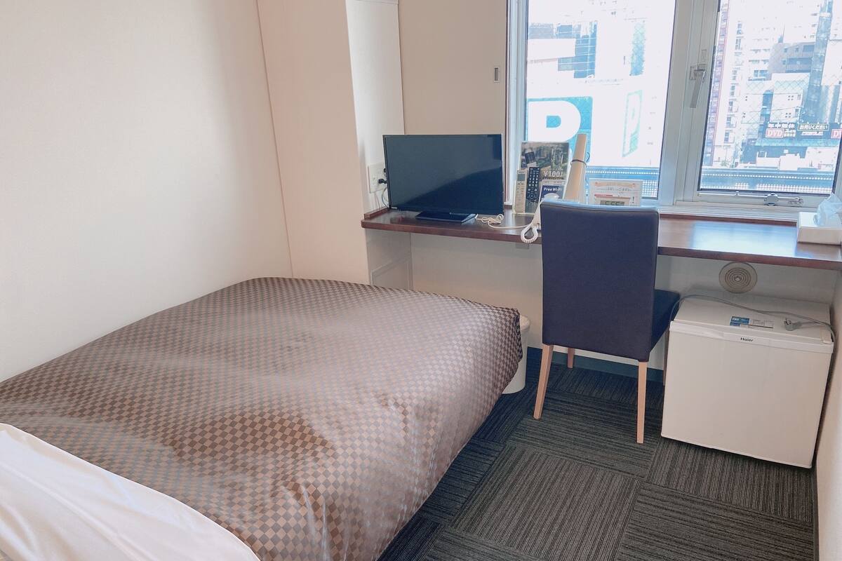 Ein Hotelzimmer mit Bett, Schreibtisch, Stuhl und einem kleinen Heizgerät.