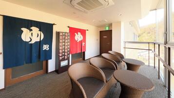 A hotel room with a balcony, wicker furniture, and Japanese flags.