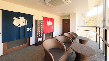 Habitación de hotel con balcón, mobiliario de mimbre y banderas japonesas.