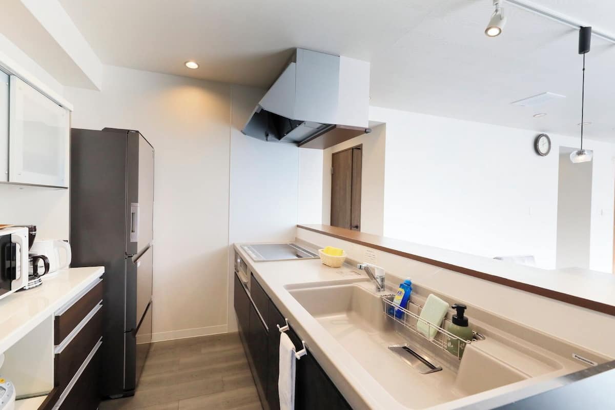 A modern kitchen with a microwave, refrigerator, sink, and a window.