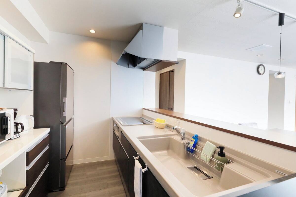 A modern kitchen with a microwave, refrigerator, sink, and a window.