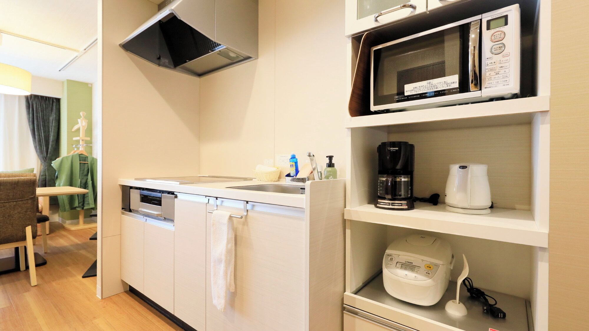 A compact kitchenette with a microwave, coffee maker, and a rice cooker.