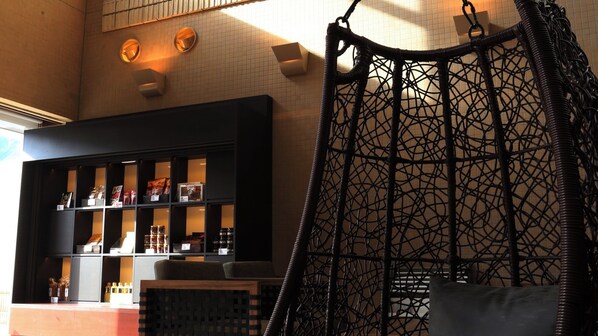 A room with a black shelving unit displaying various items, a hanging chair, and a patterned wall.