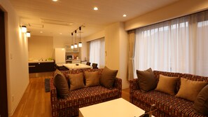 Ein modernes Wohnzimmer mit gemusterten Sofas, einem Esstisch und einer Küche im Hintergrund.