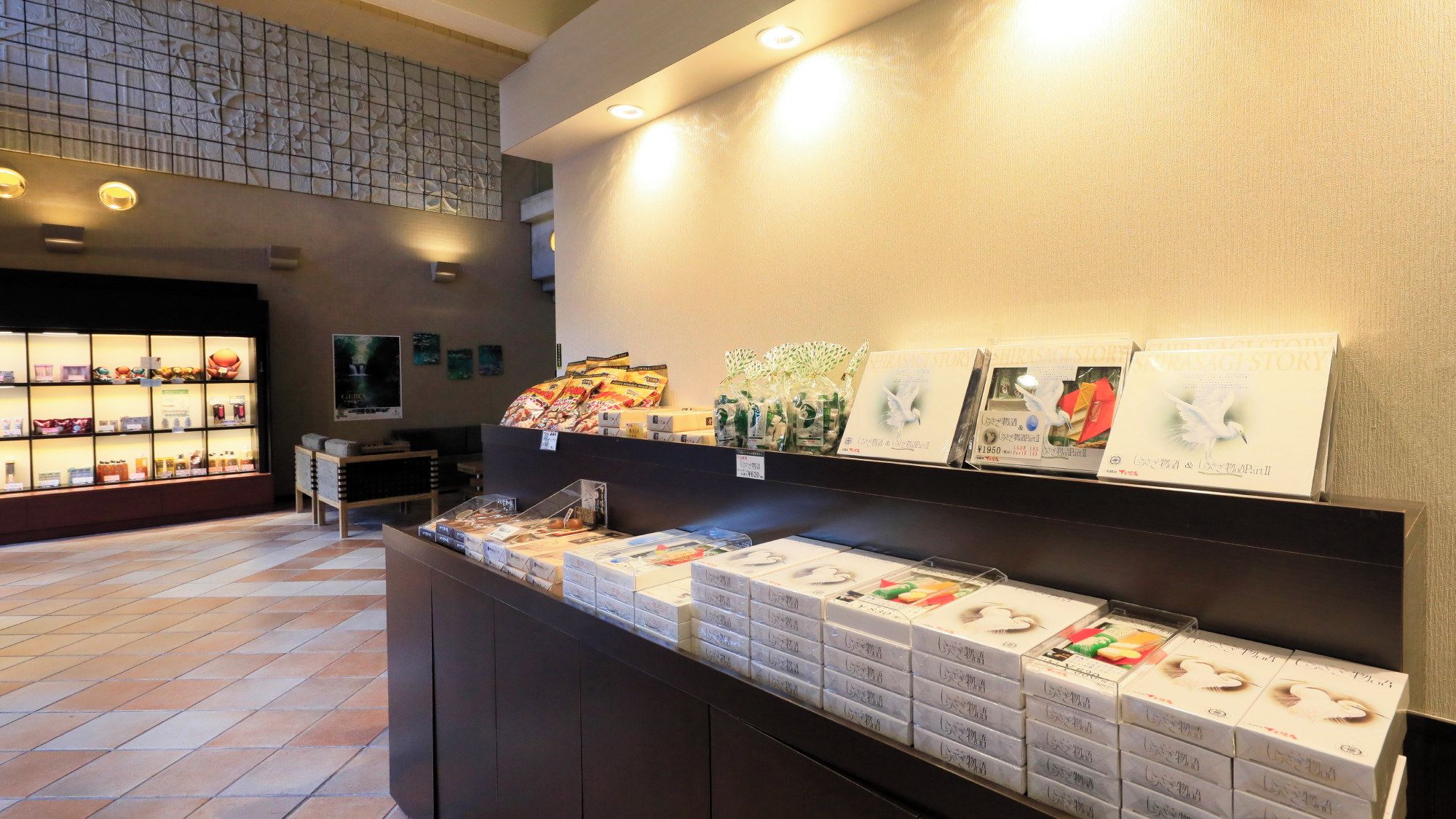 En hotellobby med en receptionsdisk där olika förpackade varor visas och en vägg med ett dekorativt mönster.