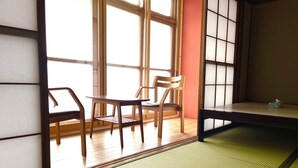 A traditional Japanese room with tatami flooring, a low table, and wooden furniture. - Green House Goryokaku (Hakodate)