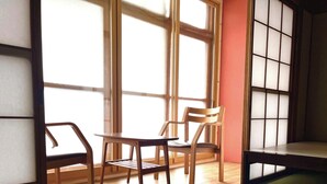 A room with a wooden table, two chairs, a window with a view, and a small table with a tissue box. - Green House Goryokaku (Hakodate)