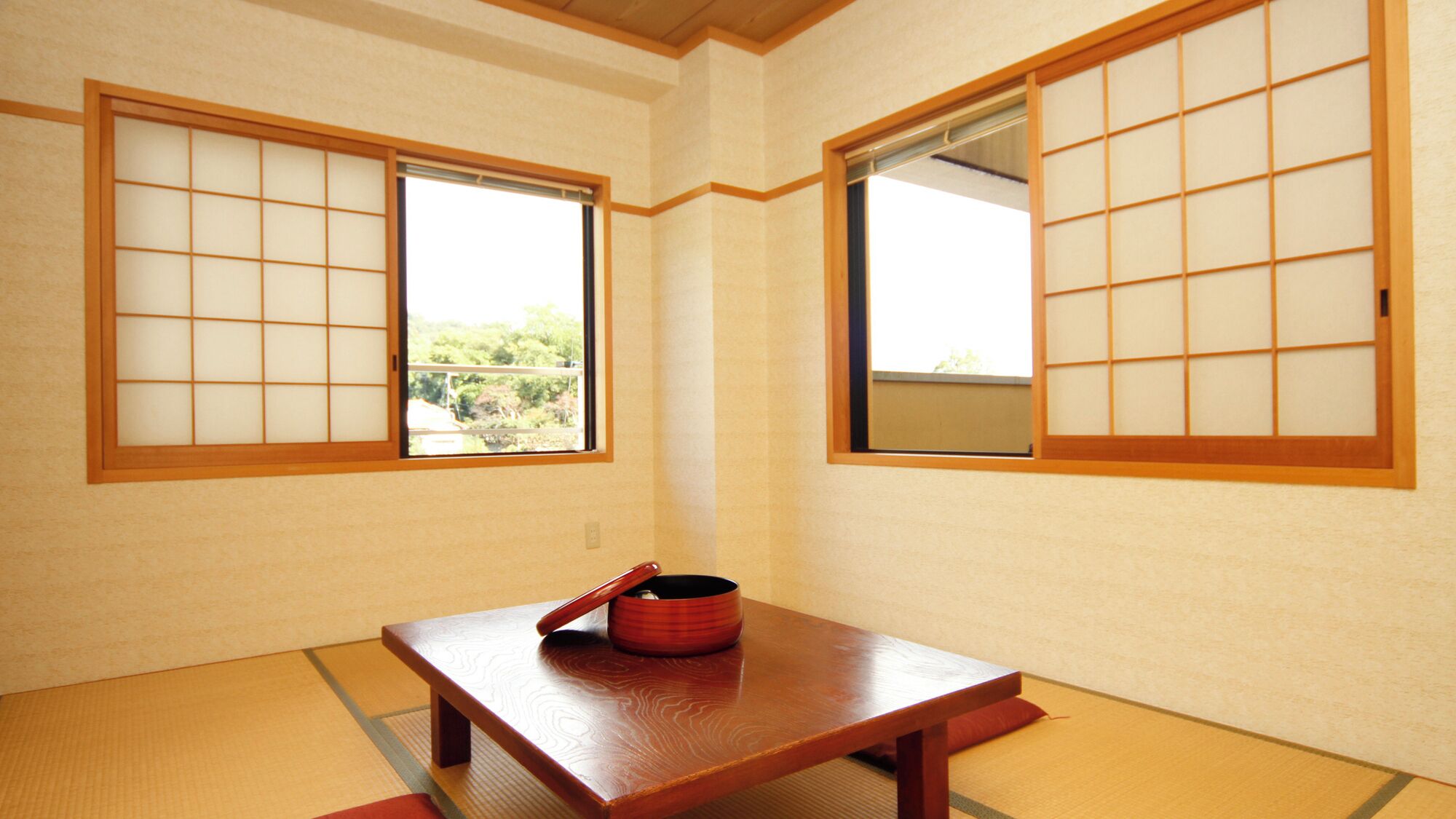 A traditional Japanese room with tatami flooring, shoji screens, and a low wooden table with a red container.