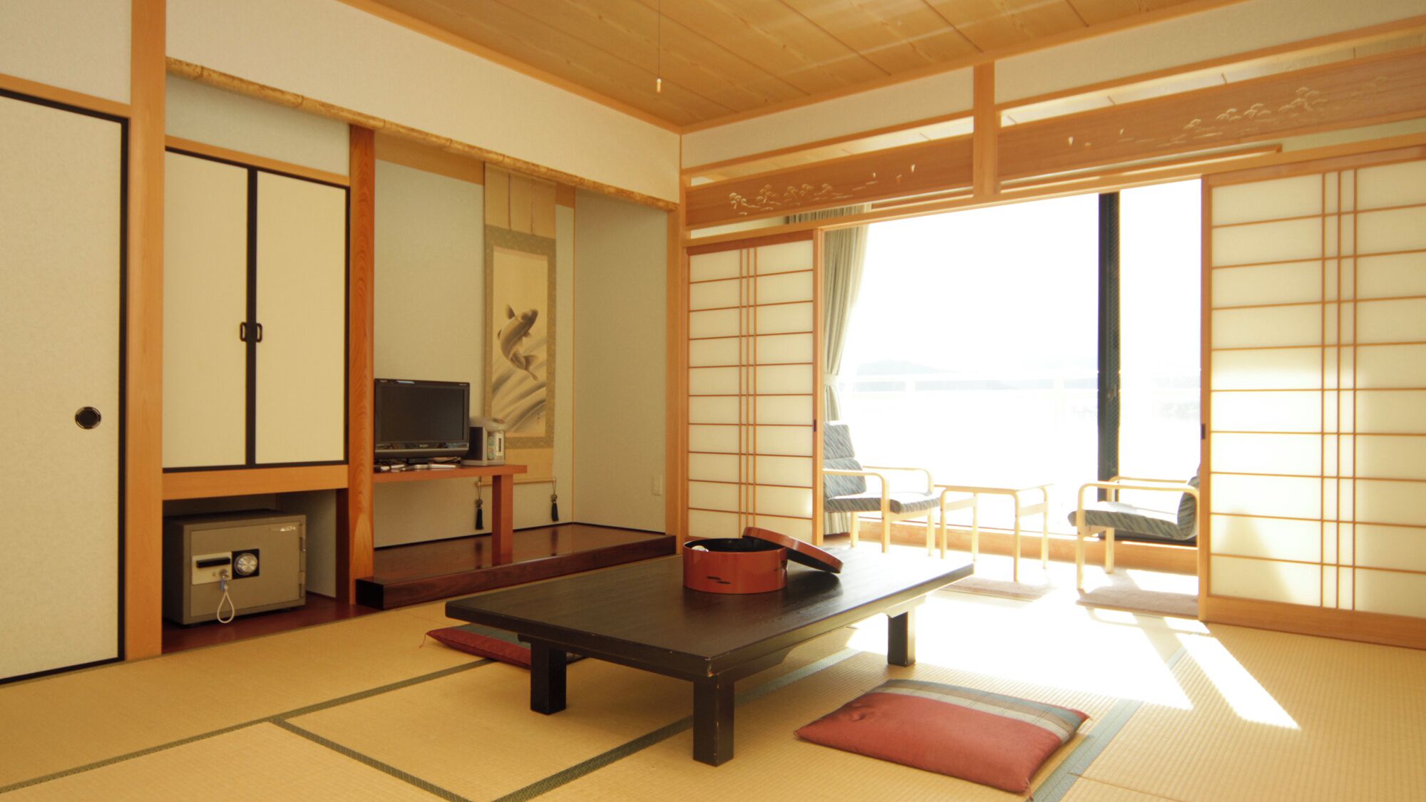 A traditional Japanese room with tatami flooring, a low table, a television, and sliding doors.