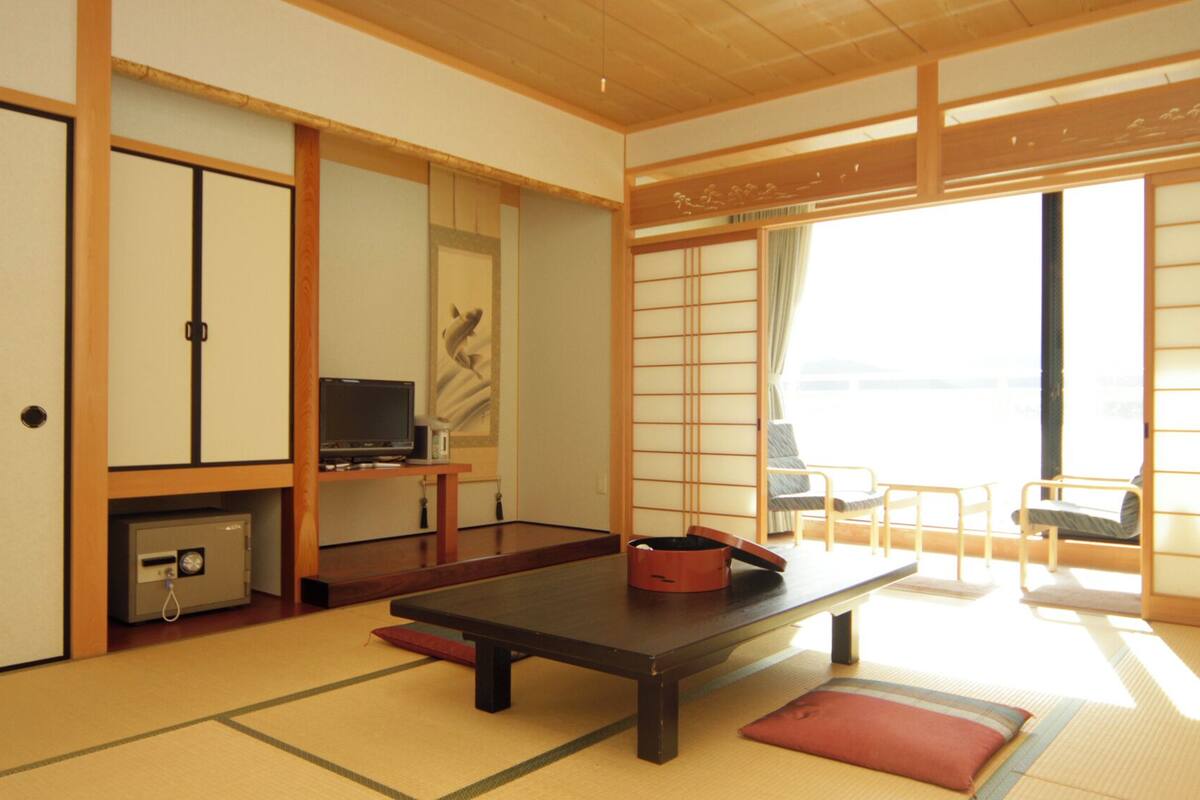 A traditional Japanese room with tatami flooring, a low table, a television, and sliding doors.