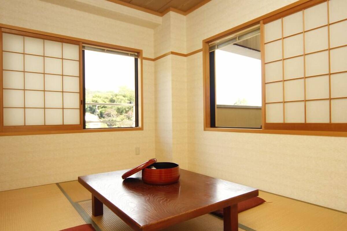 A traditional Japanese room with tatami flooring, shoji screens, and a low wooden table with a red container.