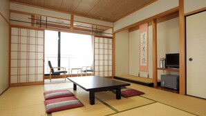 A traditional Japanese room with tatami flooring, a low table, a sofa, and a television. - Shofuso (Miyazu)