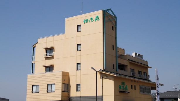A multi-story building with a flat facade, multiple windows, and a sign with green characters. - Shofuso (Miyazu)