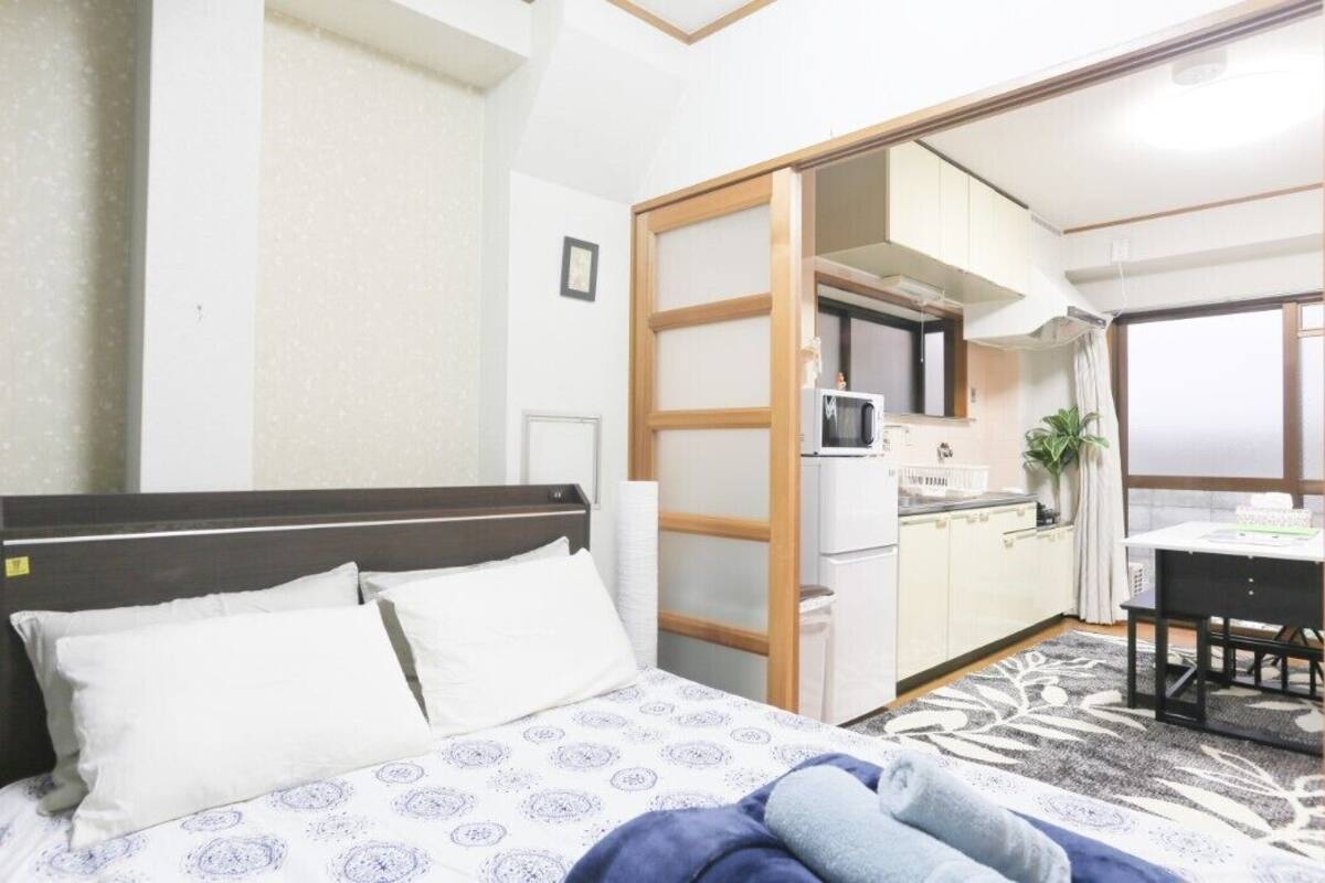 Ein Hotelzimmer mit einem Bett, einer kleinen Küchenzeile, einem Essbereich und einer Schiebetür zu einem weiteren Raum.