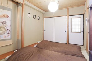 A bedroom with a bed, wooden ceiling, and a wall with three framed pictures. - Comodita Takeyacho 1f (Kyoto)