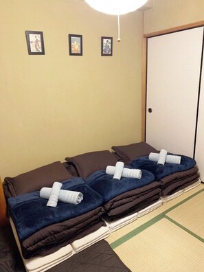 A room with a sofa bed, a door, and three framed pictures on the wall. - Comodita Takeyacho 1f (Kyoto)