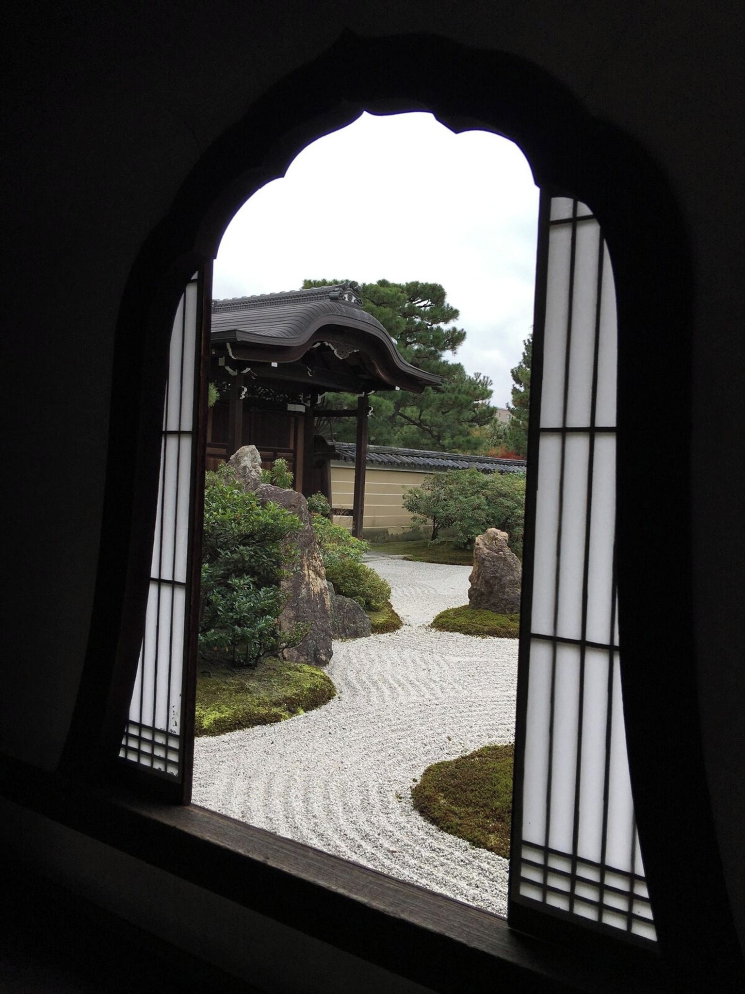 Un edificio japonés tradicional con un sendero de grava y un jardín de rocas.