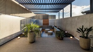 A rooftop terrace with a wooden deck, seating area, potted plants, and a pergola structure. - Terrace Hotel f (Osaka)